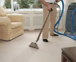 Carpet cleaning professional removing dirt and stains with a hot-water extraction tool in a home, Des Moines, IA.