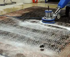 Professional rug cleaning with a rotary floor machine and shampoo foam, deep-cleaning an area rug, in Des Moines, IA.